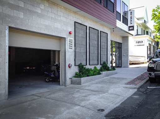Parking garage entrance with motorcycle and landscaping at 68 Beale Apartments, Massachusetts, 02169